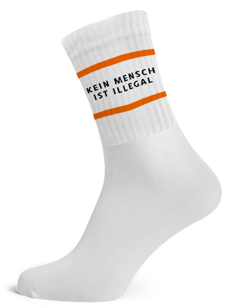 Weiße Tennissocken mit Schriftzug "Kein Mensch ist illegal", mit orangen Streifen.