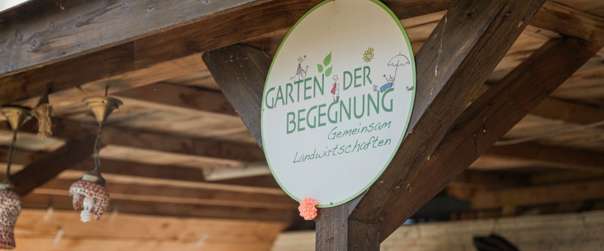 Rundes Schild mit der Aufschrift ”Garten der Begegnung, Gemeinsam Landwirtschaften”. Foto: Louai Abdul Fattah
